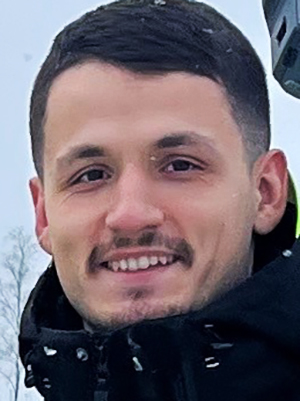 En ung man med mörkt hår ler