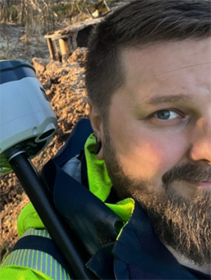 En man med skägg ler in i kameran