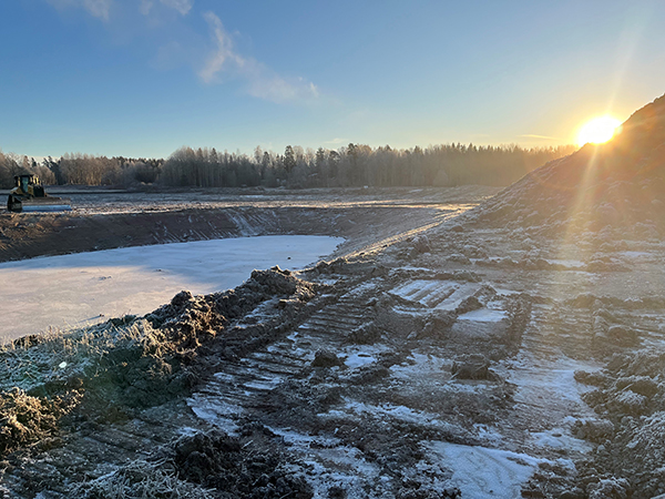 Bilden visar arbetet som pågår, en grävmaskin vid en uppgrävd yta, i svag novembersol